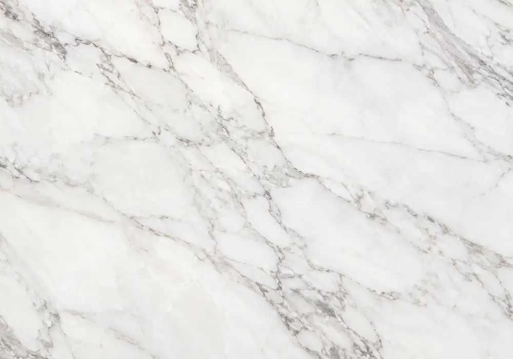 Arabiscato countertop on polished kitchen island with looping silver-grey veins, honed flooring and bathroom vanity area.