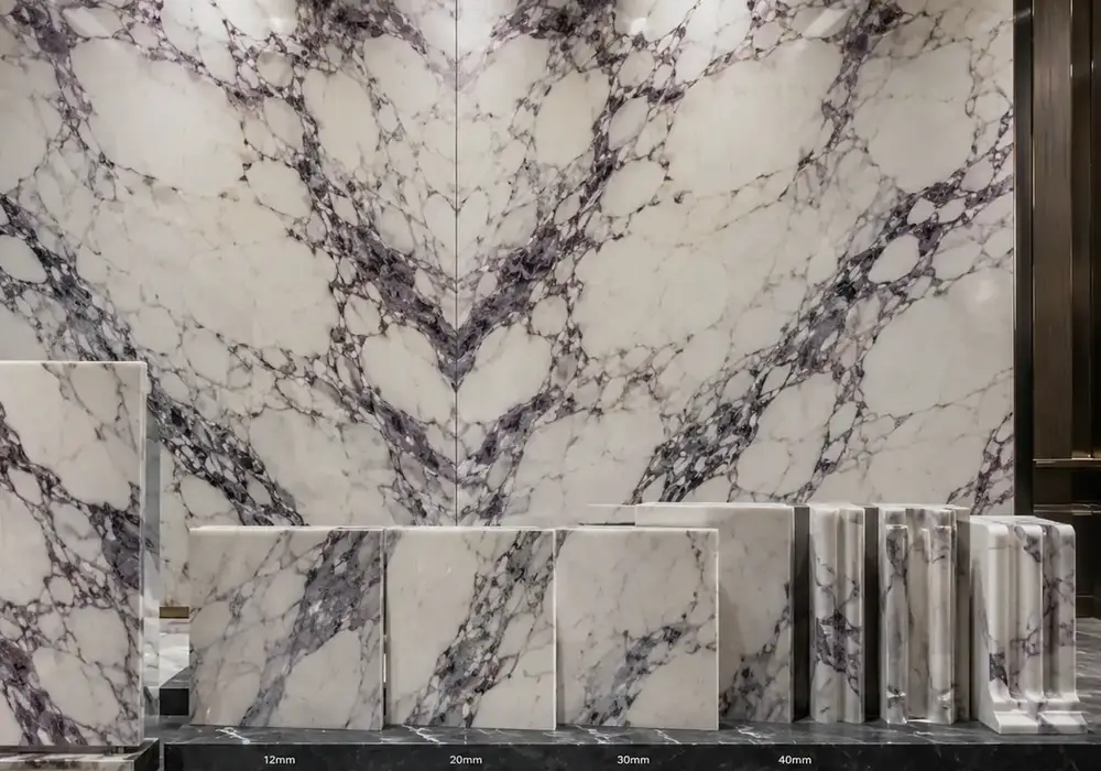 heavily brecciated slabs bookmatched across a reception wall and counter with ivory islands and bold burgundy-purple veins.