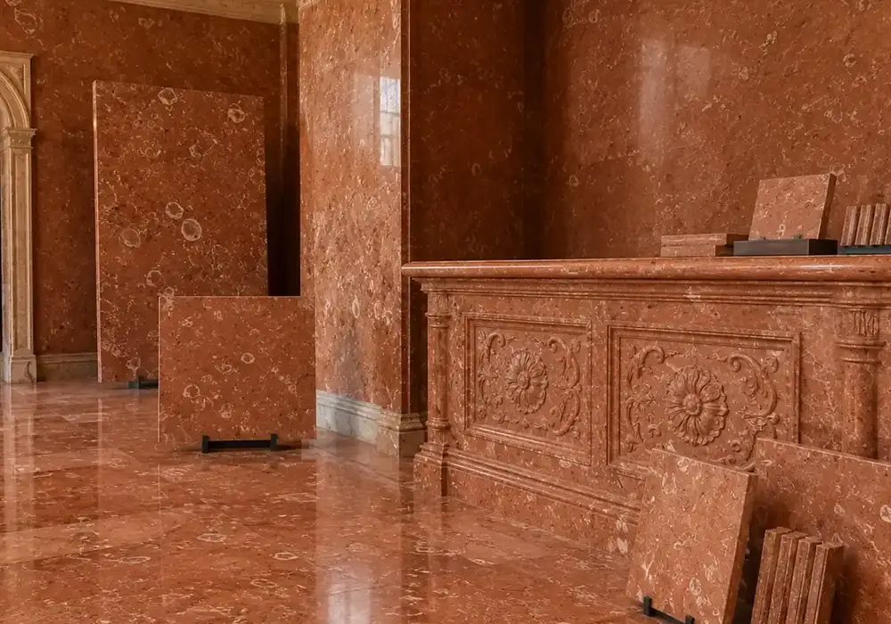 red Verona marble shown on a polished red and brown slab with clouded movement and fossil details, across a luminous surface.