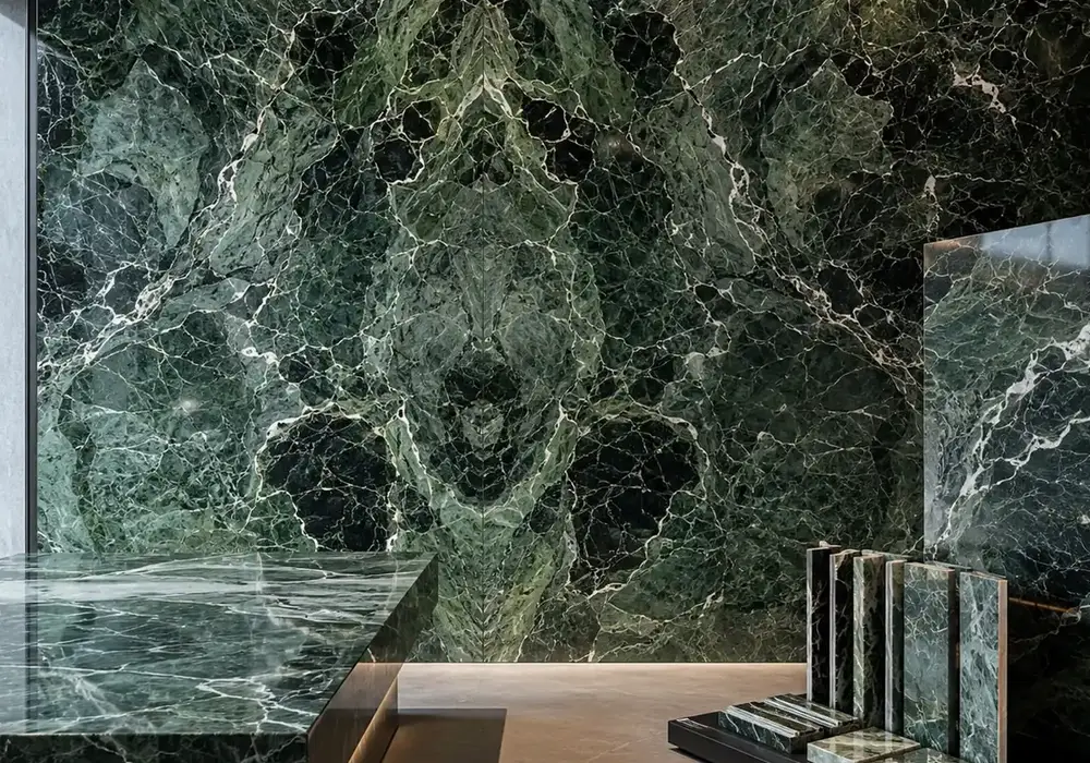 sophisticated green feature stone across a statement wall, flooring and a sculptural countertop, with natural slab variation.